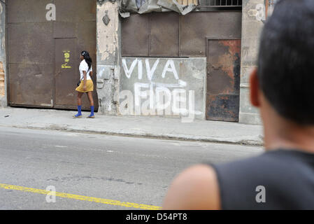 11 mars 2013 - La Havane, Cuba - UN Bici-Taxi (taxi vélo pilote) s'arrête pour hurler à une femme comme elle marche près de grafitti politique en faveur du Président Fidel Castro à La Havane, Cuba le 12 mars, 2013. (Crédit Image : © Josh Edelson/ZUMAPRESS.com) Banque D'Images