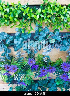 Des fleurs en plastique et de plantes en pot en bois comme un jardin vertical. Banque D'Images