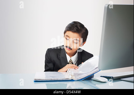 Garçon imitant comme homme d'affaires de l'examen des documents Banque D'Images