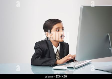 Garçon imitant comme businessman travaillant sur un pc de bureau Banque D'Images