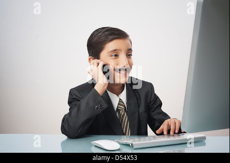 Garçon imitant comme images tout en travaillant sur un pc de bureau Banque D'Images