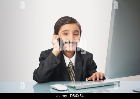 Garçon imitant comme images tout en travaillant sur un pc de bureau Banque D'Images