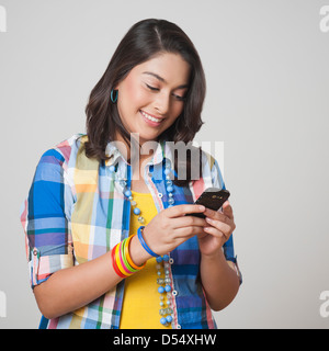 Teenage girl text messaging with a mobile phone and smiling Banque D'Images