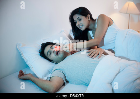 Femme essayant de fixer sur son mari clothespin ronflement nez on bed Banque D'Images