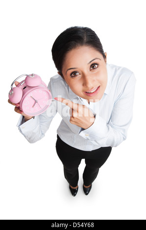 Portrait of a businesswoman pointing vers un réveil Banque D'Images