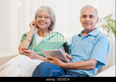 L'homme à l'aide d'une tablette numérique avec sa femme à l'écoute de la musique avec un lecteur MP3 Banque D'Images