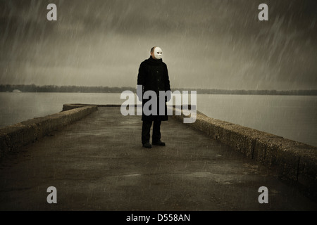 L'homme avec masque blanc près de la rivière et jour de pluie Banque D'Images