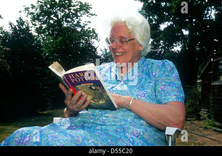 Femme âgée lecture Harry Potter et le Prisonnier d'Azbakan roman dans son jardin, Teddington, Middlesex, Royaume-Uni. Banque D'Images