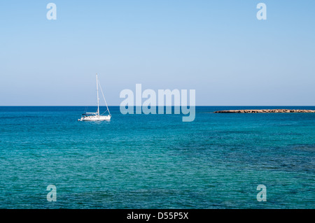 Petit yacht blanc près de l'île rocky de Chypre Banque D'Images