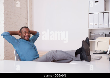 Black businessman sitting at desk with feet up Banque D'Images