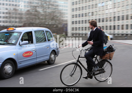 Un cycliste entrer dans un rond-point à Londres, en Angleterre, un taxi passe déjà sur le rond-point Banque D'Images