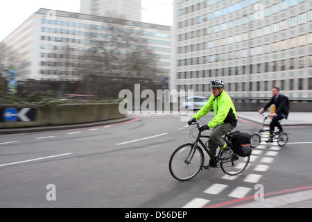 Deux cyclistes entrer dans un rond-point à Londres, en Angleterre. Banque D'Images