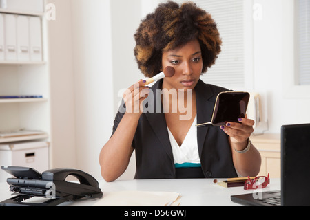 African American Woman applying makeup in office Banque D'Images