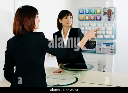 Mixed Race businesswoman using computer in mirror Banque D'Images