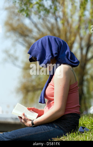 Cracovie, Pologne, une jeune femme assise dans un pré sur la Vistule et lit Banque D'Images