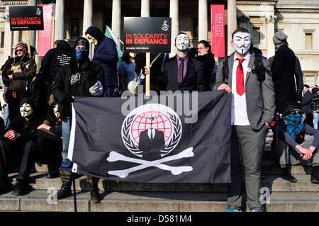 Un groupe de manifestants, certains d'entre eux portant des masques anonyme lors d'un rassemblement à Trafalgar Square, Londres, Royaume-Uni. Banque D'Images