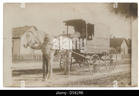 Une image photographique d'un homme et deux garçons avec un chariot tiré par un cheval, capturant une scène rurale du Texas. L'image reflète la vie et les transports au début du XXe siècle dans le sud-ouest des États-Unis. Banque D'Images