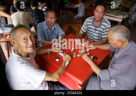 Les hommes jouant le populaire jeu chinois antique de Mahjong dans un temple en Chine. Banque D'Images