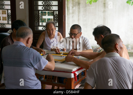 Les hommes jouant le populaire jeu chinois antique de Mahjong dans un temple en Chine. Banque D'Images