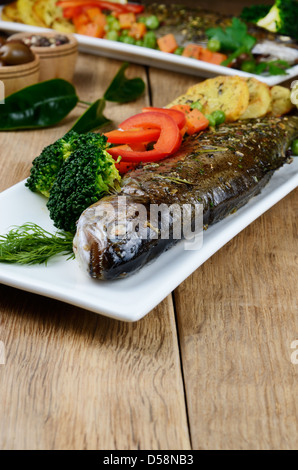 Truite au four avec un plat et des légumes sur la table de cuisine Banque D'Images