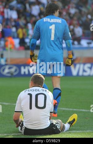 L'Allemagne Lukas Podolski se trouve sur le terrain derrière le gardien de la Serbie Vladimir Stojkovic, pendant la Coupe du Monde 2010 GROUPE D match entre l'Allemagne et la Serbie au Nelson Mandela Bay Stadium à Port Elizabeth, Afrique du Sud 18 juin 2010. La Serbie a gagné 1-0. Photo : Marcus Brandt dpa - veuillez vous reporter à http://dpaq.de/FIFA-WM2010-TC Banque D'Images