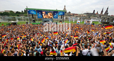 Fans de l'équipe nationale de football allemande cheer et célébrer comme ils regardent la Coupe du monde match de football entre l'Allemagne et le Ghana dans la zone d'affichage public sur le remblai de l'Elbe à Dresde, Allemagne, 23 juin 2010. Situé sur le côté opposé est le centre historique de Dresde avec la Frauenkirche, le palais et la tour de la cathédrale. Photo : Arno Burgi Banque D'Images