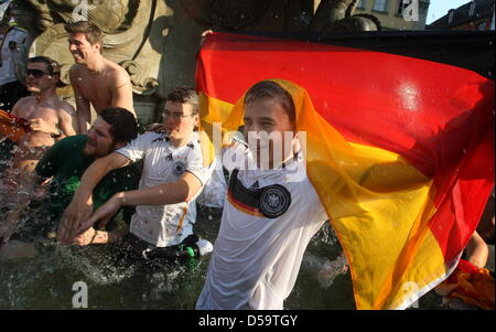 Soccer fans célèbrent la victoire de l'équipe nationale allemande de football contre l'Argentine dans une fontaine à Würzburg (Basse Franconie), Allemagne, 03 juillet 2010. Après ce résultat, l'équipe allemande prend part à la demi-finale de la Coupe du Monde 2010. Photo : Karl-Josef Opim Iby/dpa Banque D'Images