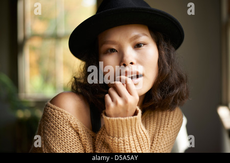 Belle jeune modèle asiatique portant chapeau noir et marron pour homme à la maison. Banque D'Images