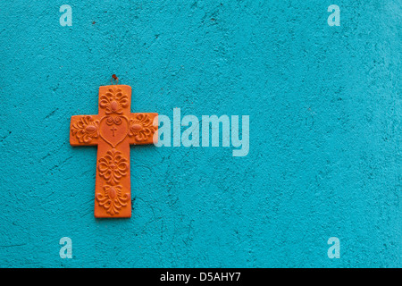 Croix en terre cuite sur un mur turquoise d'une maison traditionnelle mexicaine Banque D'Images