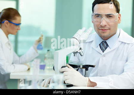 Portrait d'un(e) scientifique étudiant les résultats de l'expérience sous le microscope Banque D'Images