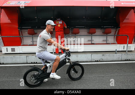 Formule 1 allemande racedriver Michael Schumacher (Mercedes GP) (R) à travers la voie des stands sur un vélo électrique à l'Hockenheimring à Hockenheim, Allemagne, 22 juillet 2010. Photo : Jens Buettner Banque D'Images