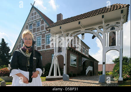 Un guide en costume traditionnel pose devant une porte ornée de Jork, Allemagne, 03 août 2010. En raison de la destruction de la DEUXIÈME GUERRE MONDIALE, il n'y a que 14 portes traditionnelles telles la gauche dans la région de l'Altes Land de Basse-Saxe. Photo : Ingo Wagner Banque D'Images