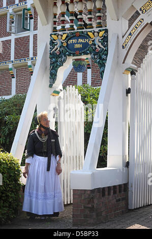 Un guide en costume traditionnel pose devant une porte ornée de Jork, Allemagne, 03 août 2010. En raison de la destruction de la DEUXIÈME GUERRE MONDIALE, il n'y a que 14 portes traditionnelles telles la gauche dans la région de l'Altes Land de Basse-Saxe. Photo : Ingo Wagner Banque D'Images