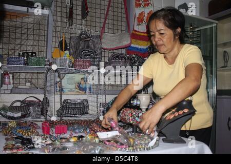 Une femme présente des colliers qui sont faites d'ordures de Manille, Philippines, janvier 2010. Dans un atelier en Tondo, les gens faire des bijoux et sacs de déchets jetés. Environ 30 familles d'améliorer leurs revenus et conditions de vie en vendant leurs produits qui sont en demande d'articles de mode à Londres.Photo : Christiane Oelrich Banque D'Images