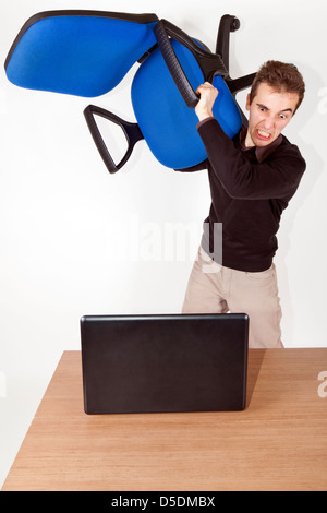 L'homme d'affaires en colère isolé avec chaise de bureau dans sa main au-dessus de sa tête prêt à détruire un ordinateur portable Banque D'Images