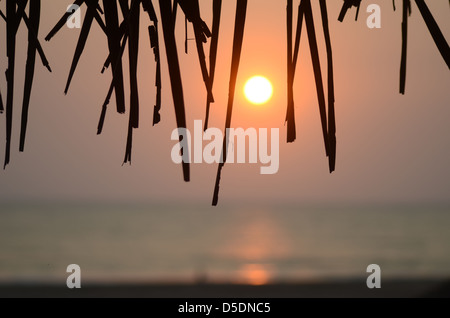 Coucher de soleil sur la mer sur un autre jour au paradis, Goa, Inde silhouetting le toit d'une cabane de plage Banque D'Images