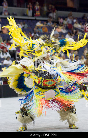 Une photographie du Powwow de 2005, capturant une danseuse amérindienne dans un costume coloré à plumes. Le danseur effectue une cérémonie traditionnelle devant une foule, reflétant le dynamisme et la signification culturelle de l'événement. Banque D'Images
