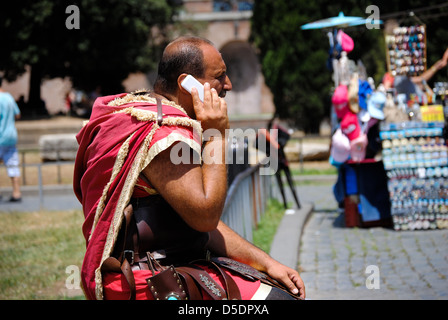 Un homme habillé dans un costume de la Rome antique sur le téléphone devant le Colisée Banque D'Images