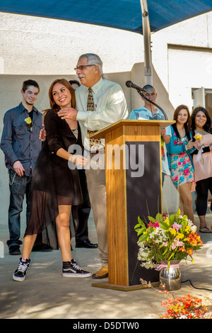 Le directeur d'une continuation de la Californie du Sud high school. félicite un cadre habillé étudiante à l'obtention du diplôme. Banque D'Images