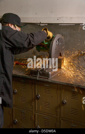 Étincelles voler comme un élève du secondaire utilise une scie circulaire pour couper un tuyau métallique en auto shop class à San Clemente, CA. Banque D'Images