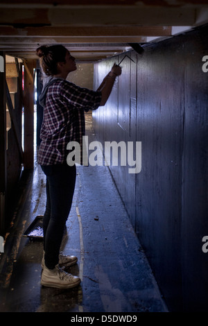 La silhouette d'un étudiant en théâtre de l'école secondaire utilise un rouleau à peindre à préparer un ensemble pour une école jouer à San Clemente, CA. Banque D'Images