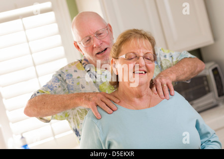 Happy Senior Adulte mari épouse donnant une épaule frotter dans la cuisine. Banque D'Images