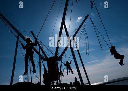 Pays de Galles Aberystwyth UK, le dimanche de Pâques, le 31 mars 2013. Les enfants appréciant les soleil du printemps, jouant sur les trampolines bunjee Aberystwyth sur la promenade. La persistance des vents de l'Est signifie que cela a été le plus froid depuis mars 1962, et les températures sont en dessous de la moyenne pour la première semaine d'avril photo ©keith morris Banque D'Images