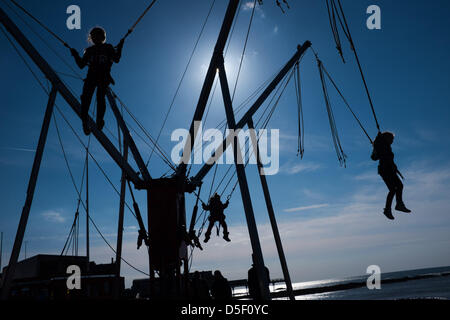 Pays de Galles Aberystwyth UK, le dimanche de Pâques, le 31 mars 2013. Les enfants appréciant les soleil du printemps, jouant sur les trampolines bunjee Aberystwyth sur la promenade. La persistance des vents de l'Est signifie que cela a été le plus froid depuis mars 1962, et les températures sont en dessous de la moyenne pour la première semaine d'avril photo ©keith morris Banque D'Images