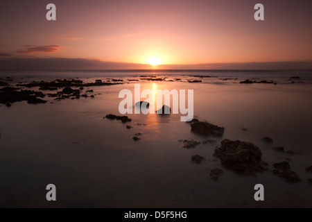 Le coucher du soleil sur une plage rocheuse, dans le centre touristique de Las Americas sur l'île canarienne de Tenerife Espagne Banque D'Images