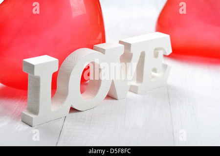 Mot amour en bois avec des ballons coeur blanc sur fond de bois Banque D'Images
