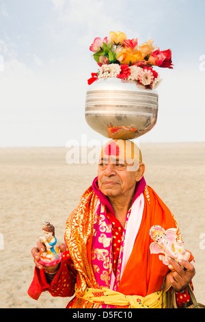 L'équilibrage Sadhu chaudron en acier inoxydable contenant des fleurs artificielles sur sa tête pendant le festival Kumbh Mela Allahabad Uttar Banque D'Images