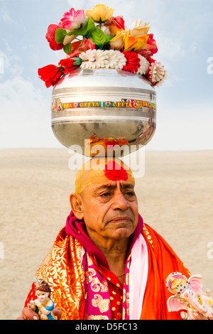 L'équilibrage Sadhu chaudron en acier inoxydable contenant des fleurs artificielles sur sa tête pendant le festival Kumbh Mela Allahabad Uttar Banque D'Images