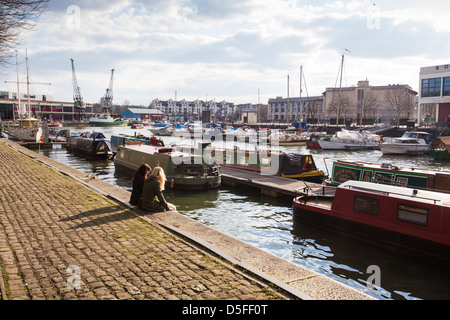 Deux filles assis au bord de l'eau sur Narrow Quay dans le port de Bristol à Bristol, Royaume Uni Banque D'Images