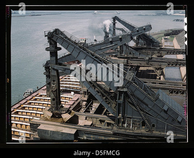 L'image représente les quais de minerai de Pennsylvania Railroad à Cleveland, Ohio, où le minerai est déchargé d'un cargo de lac à l'aide de déchargeurs Hulett. Ce procédé mécanique met en lumière les avancées industrielles du début du XXe siècle dans le domaine de la navigation et du transport. Banque D'Images